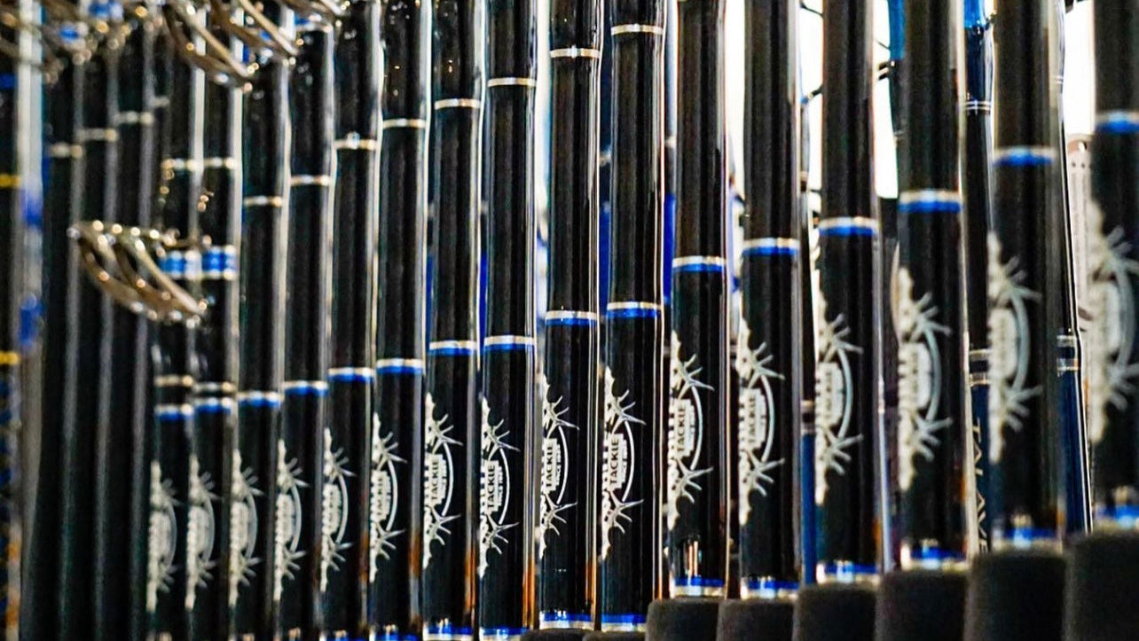 Row of black and blue white's tackle fishing rods with engraved designs in a tackle shop setting