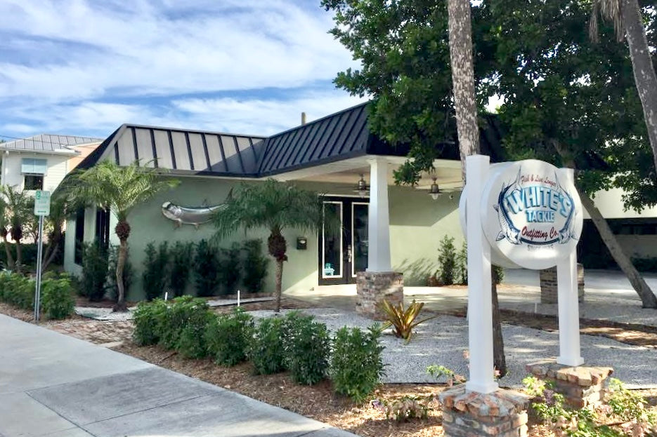 White's Tackle store front building exterior with a sign in front, surrounded by trees and plants.