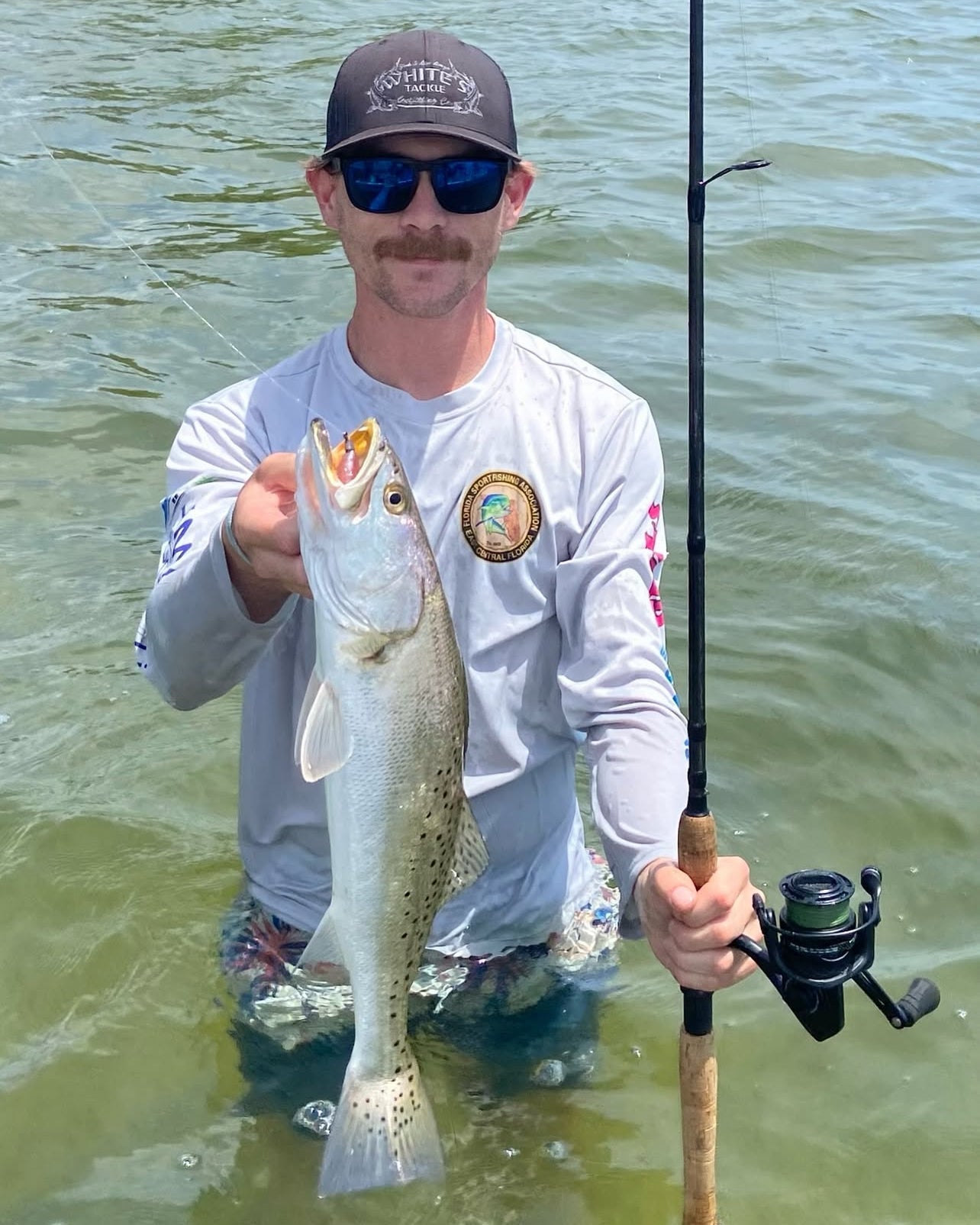 Man holding a fish and fishing rod in water