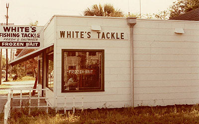 Vintage-style photo of a tackle shop named 'White's Tackle' with a sign for 'Frozen Bait'.